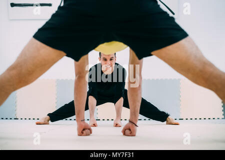 Vista attraverso le mans gambe di amici facendo esercizio di stretching Foto Stock