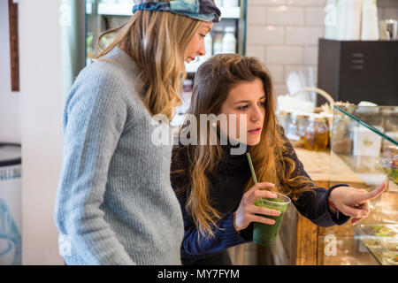 Giovane donna e amico guardando il cibo fresco vetrina in cafe Foto Stock