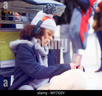 Ragazza guardando il passaporto in airport lounge di partenza Foto Stock