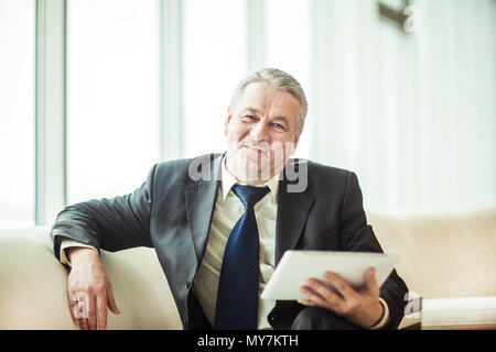 Sorridente imprenditore esperto con tavoletta digitale seduti sul divano in ufficio Foto Stock