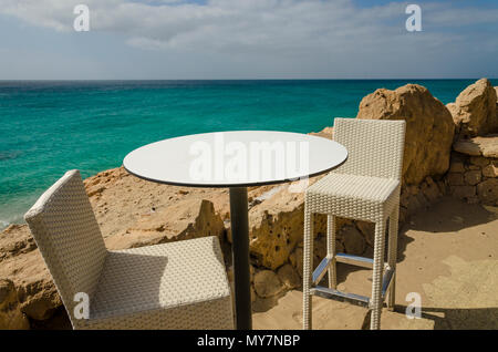 Il cafe bar con vista sul mare. Due barre bianche sedie e un tavolo su un lungomare con vista dell'Oceano Atlantico sulla Fueteventura isola. Foto Stock