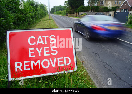 Il traffico che passa un cartello di segnalazione di gatti occhi rimossi sulla strada da percorrere prima di resurfacing lavorare Leeds REGNO UNITO Foto Stock