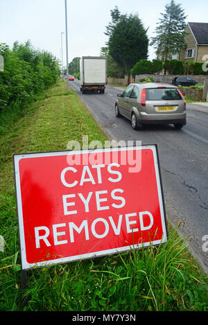 Il traffico che passa un cartello di segnalazione di gatti occhi rimossi sulla strada da percorrere prima di resurfacing lavorare Leeds REGNO UNITO Foto Stock