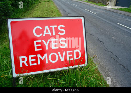 Il traffico che passa un cartello di segnalazione di gatti occhi rimossi sulla strada da percorrere prima di resurfacing lavorare Leeds REGNO UNITO Foto Stock