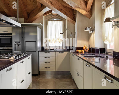 Moderna cucina interno nella camera mansardata con cucina a isola e soffitto in legno Foto Stock
