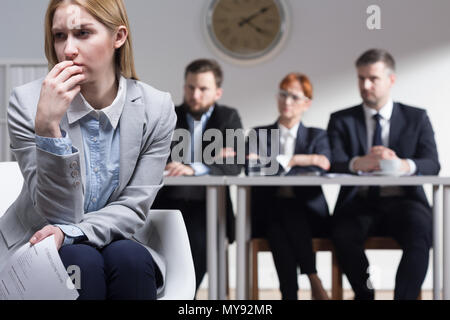 Triste donna azienda CV e tre imprenditori seduto accanto a tabella Foto Stock