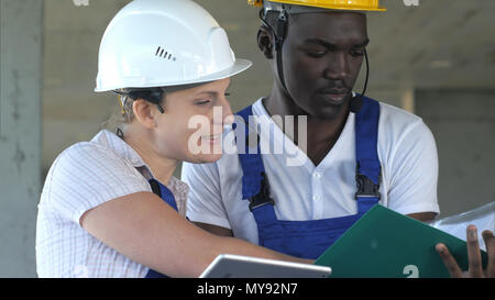 Due lavoratori aventi la conversazione e utilizzando computer tablet Foto Stock