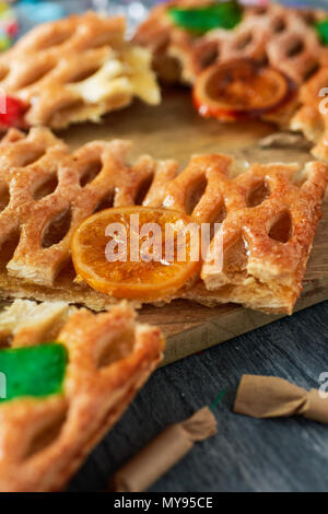 Primo piano di alcuni pezzi di una coca de Sant Joan, un tipico dolce torta piatta dalla Catalogna, Spagna, mangiato su Saint Johns Eve, su un tavolo rustico, accanto a s Foto Stock