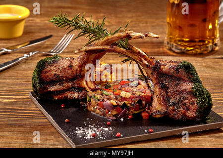 Costolette di agnello grigliate sul tagliere con arrosti di verdure ed erbe Foto Stock