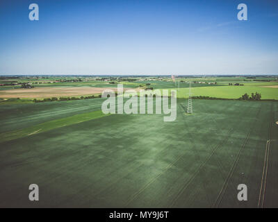 Vista aerea della linea ad alta tensione oltre il campo di grano verde Foto Stock