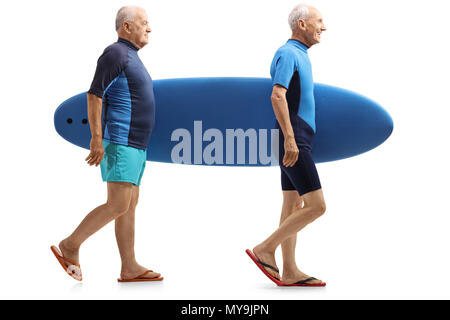 Per tutta la lunghezza del profilo di colpo due anziani surfers camminare e trasportare una tavola da surf isolati su sfondo bianco Foto Stock