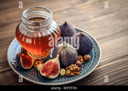 Il miele di fichi freschi e i dadi su sfondo di legno closeup Foto Stock