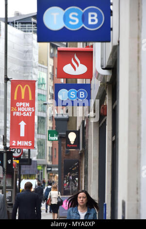 La gente a piedi passato le filiali bancarie del TSB e banche di Santander, Holborn, Londra centrale, con un McDonald poster promozionali in background. Foto Stock