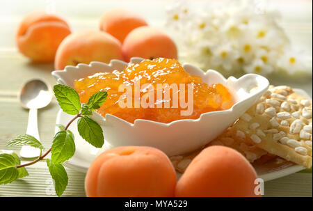 Confettura di albicocche nella ciotola bianco con frutta intorno - primo piano Foto Stock