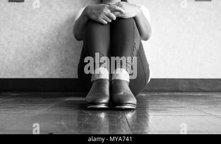 Versione in bianco e nero di toccare la ballerina seduta verso il basso e tenendo le gambe Foto Stock