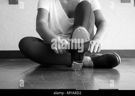 Versione in bianco e nero di toccare la ballerina scorrevole su di lei tocca le scarpe della dance studio durante il corso di danza Foto Stock