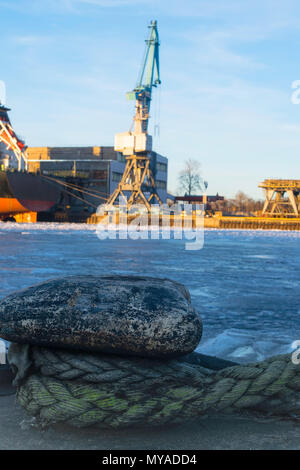 Vecchio bollard con corda verde con vista industriale. Messa a fuoco selettiva Foto Stock