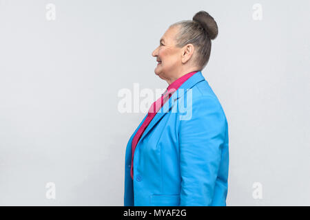 Profilo della faccina felice donna invecchiato con bun raccolti i capelli grigi. Emozioni e sentimenti. Ritratto di bello nonna espressiva con tuta blu e Foto Stock