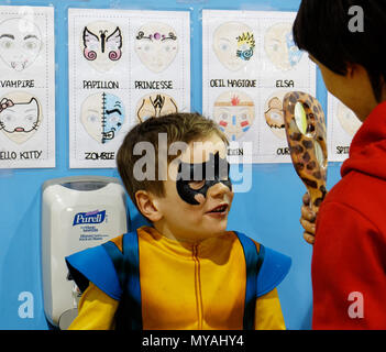 Un giovane ragazzo (6 yr old) ammirando il suo nuovo Batman faccia vernice in uno specchio Foto Stock