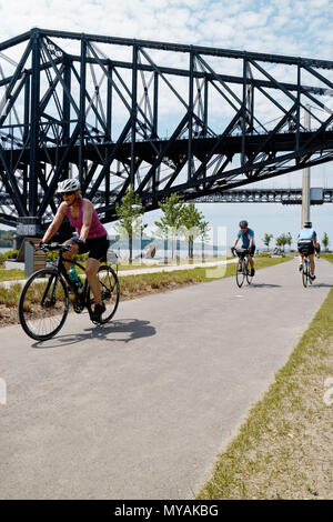 I ciclisti sulla Promenade Samuel de Champlain pista ciclabile in Quebec City, con il St Lawrence river a Pont du Québec al di là del ponte Foto Stock