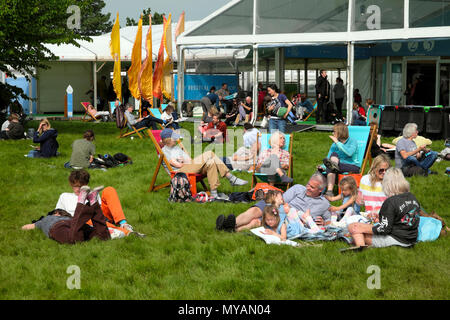 La gente seduta rilassante nella sdraio la lettura di libri di testo scorrevole sul fieno sito del festival di sole 2018 Hay-on-Wye Wales UK KATHY DEWITT Foto Stock