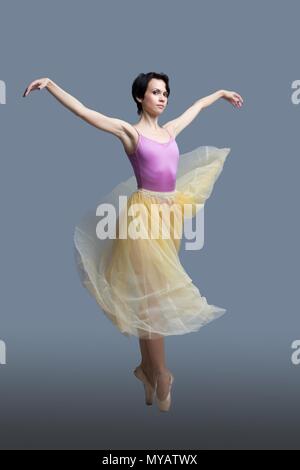 La ballerina è dancing in studio su sfondo grigio Foto Stock