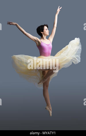 La ballerina è dancing in studio su sfondo grigio Foto Stock