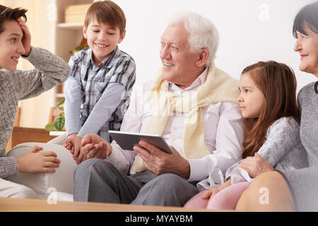 Felice nipoti il nonno di insegnamento per utilizzare un tablet Foto Stock