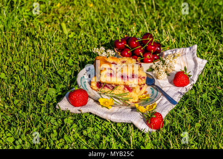 Foto orizzontale con due porzioni di torta di ciliegie. La torta viene collocato sul piattino e su asciugamano bianco. Ciotola piena di altri frutti è accanto alla torta con diversi Foto Stock