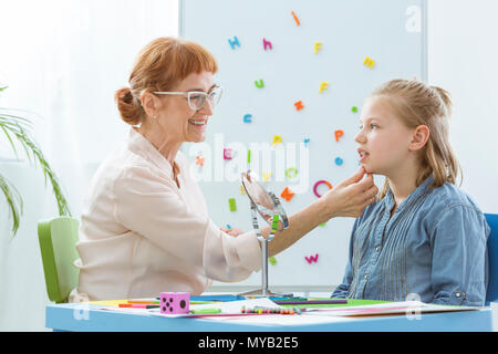 Logopedista esercita con il bambino nel suo ufficio luminoso Foto Stock