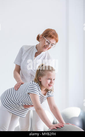 Bambino con deformità della colonna vertebrale che esercitano con terapista della riabilitazione room Foto Stock