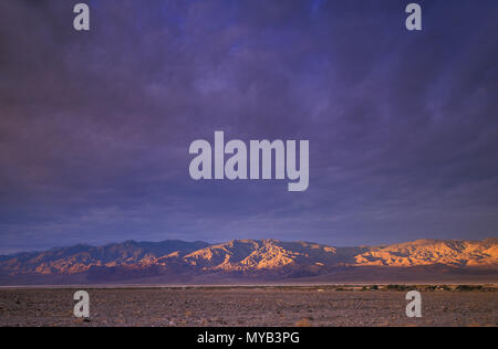 Alba nella Valle della Morte, con sole sopra la gamma della montagna con il modello di cloud computing, Death Valley, CA, Stati Uniti d'America Foto Stock