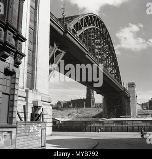 Degli anni Cinquanta, foto storiche, una vista dal basso, dalla banchina del Tyne Bridge, un arco gthrough ponte sul fiume Tyne, che collega la città di Newcastle alla città di Gateshead, Inghilterra, Regno Unito. è stato il più grande singolo-span bridge nel Regno Unito quando ufficialmente inaugurato dal Re Giorgio V nel mese di ottobre 1928. Foto Stock