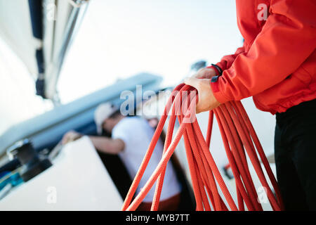 Giovane marinaio bello tirando la corda sulla barca a vela Foto Stock
