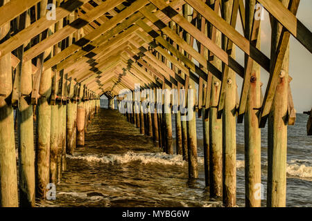 Il tardo pomeriggio di sole proietta ombre lunghe sotto il molo follia Beach, Carolina del Sud. Foto Stock