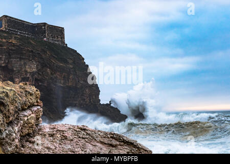 La frantumazione delle onde sulla costa in un giorno di tempesta in spiaggia a Nazare, Portogallo. Foto Stock