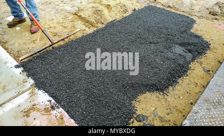 Applicare il nuovo asfalto caldo utilizzando la costruzione di strade lavoratori su asfaltatura lastricatore street lavori di riparazione Foto Stock