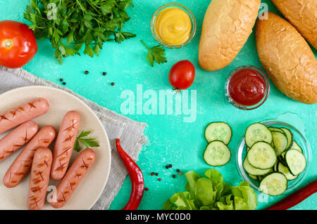 Succosa salsicce alla griglia, verdure fresche, verdi e croccanti panini su uno sfondo luminoso. Vista dall'alto. Ingredienti per hot dogs. Lay piatto. Foto Stock