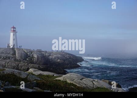 Peggy's Cove, Nova Scotia, Canada: Peggy's Point Lighthouse (1914) è avvolta nella nebbia di mattina con le onde che si infrangono sulla costa rocciosa. Foto Stock