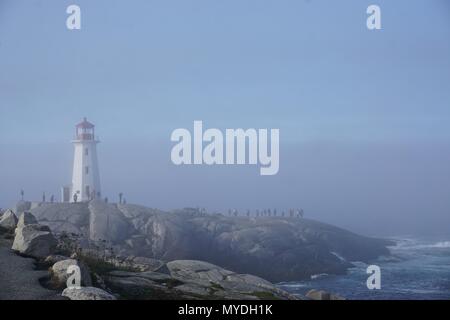 Peggy's Cove, Nova Scotia, Canada: Peggy's Point Lighthouse (1914) è avvolta nella nebbia di mattina con le onde che si infrangono sulla costa rocciosa. Foto Stock