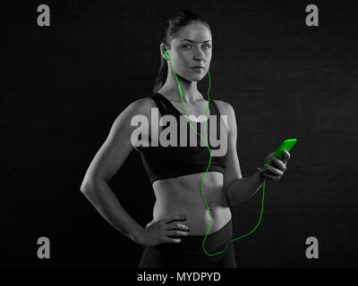 Giovane donna in sport top con lettore mp3, ritratto. Foto Stock