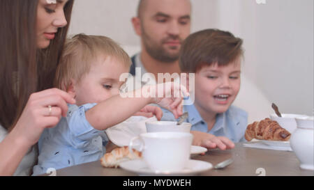 Felice famiglia giovane di quattro avente il tè al ristorante o bar o home Foto Stock