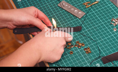 Tanner tratta cuciture con il fuoco. Processo di lavorazione in officina di close-up. Foto Stock