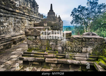 Balustraded corridoio con bassorilievi su entrambi i lati in corrispondenza del IX secolo tempio Buddhista di Borobudur e Java centrale, Indonesia Foto Stock