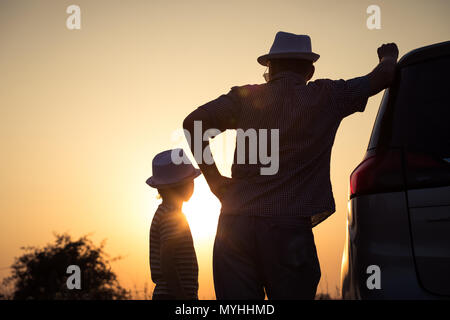 Padre e figlio giocare nel parco al tramonto. Persone divertirsi sul campo. Concetto di famiglia amichevole e di vacanza estiva. Foto Stock