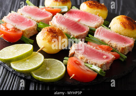 Cucinato al momento shish kebab di tonno fresco, pomodori, patate e cipolle verdi vicino sul tavolo orizzontale. Foto Stock
