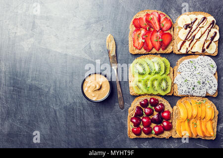 Tradizionale americana ed europea e in estate la colazione: sandwich di pane tostato con burro di arachidi, di bacche e frutti pesca, fragola, banana, ciliegia, kiwi Foto Stock