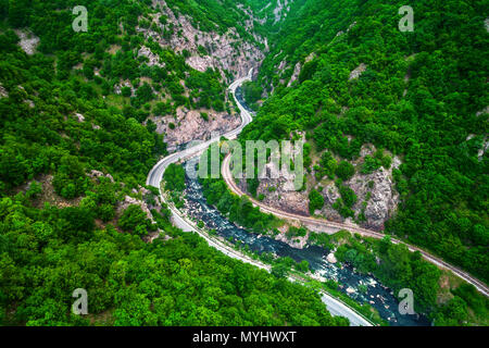 Vista aerea del drone su strada di montagna e le curve andando attraverso il paesaggio forestale Foto Stock