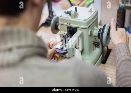 Maschio professionale skinner, pellicciaio utilizzando una speciale macchina cucitrice per la cucitura della pelle pelliccia all'atelier, workshop. Moda e marocchineria concept Foto Stock