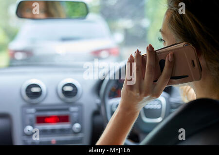 Donna alla guida mentre si utilizza il telefono cellulare Foto Stock